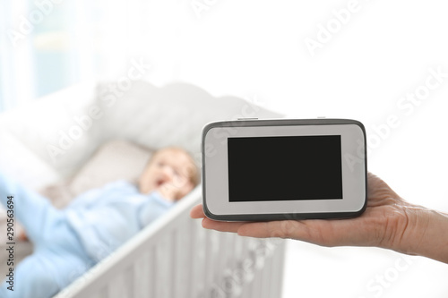 Woman Holding Baby Monitor Near Crib With Child In Room Video