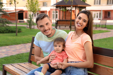 Poster - Happy family with adorable little baby on bench outdoors