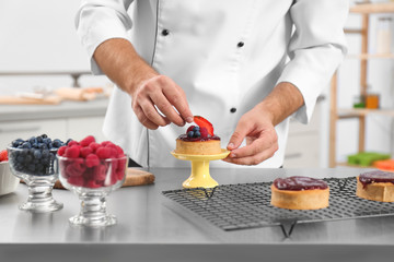 Wall Mural - Male pastry chef preparing dessert at table in kitchen, closeup