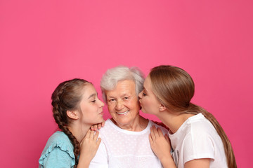 Canvas Print - Happy sisters kissing their grandmother on pink background