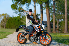 Young Boy On A Motorycle Without A Helmit Looking Behind Him On A Country Road In The Summer Doing A Burnout With Smoke