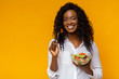 Happy african american woman eating healthy salad