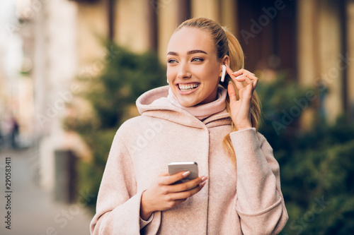 Fotomural Happy girl enjoying music in airpods, walking in city