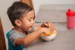 © mmg1design - A cute toddler shows interest in eating a mac and cheese lunch, and holds spoon to self-feed.
