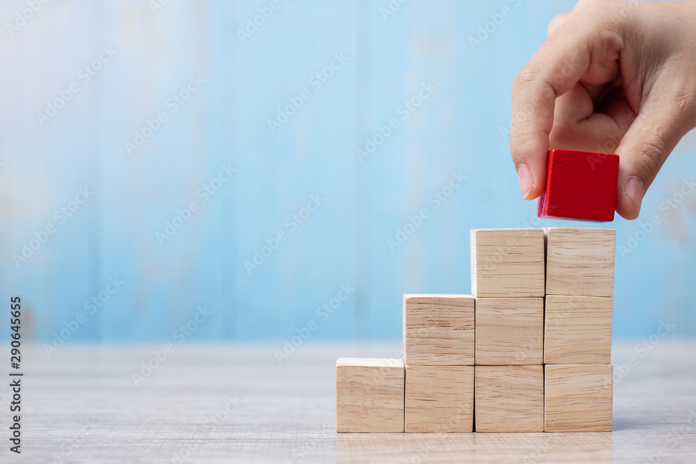 Businessman hand placing or pulling Red wooden block on the building. Business planning, Risk Management, Solution, strategy, different and Unique Concepts - obrazy, fototapety, plakaty 
