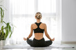 © Pixel-Shot - Young woman meditating at home, back view