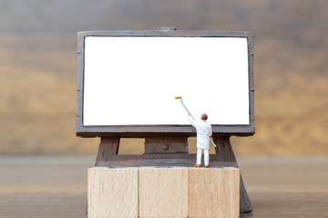 Canvas Print - Miniature people: Painter holding a brush on The stair at The front of a whiteboard and space for text