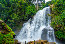 The The Grand Waterfall In The Nature Park With The Greenery Trees And Forest In The Nice Day.