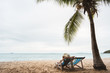 Asian woman on beach chair under tropical palm tree