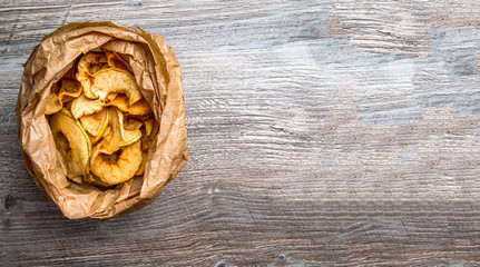 Wall Mural - Tasty apple chips in paper bag on wooden table, Healthy snack of apples Diet dish. Space for copy