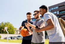 Sport, Leisure Games And Male Friendship Concept - Group Of Men Or Friends With Smartphone At Outdoor Basketball Playground