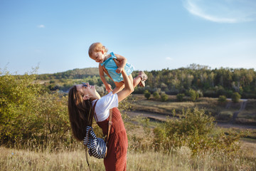 Wall Mural - Happy mother and daughter on a green field at sunset.