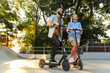 © Drobot Dean - Image of lovely pleased couple aughing while riding e-scooters