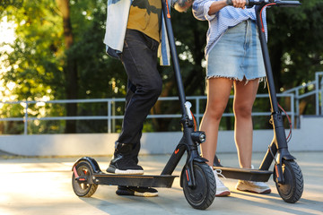 Sticker - Cropped image of young caucasian couple smiling while riding e-scooters