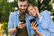 © Drobot Dean - Image of romantic couple using cellphones while resting in park