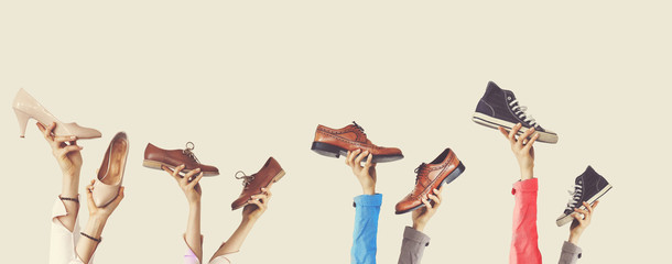 Hands holding different shoes on isolated background