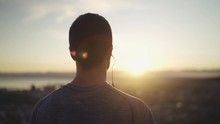Close Up Shot Of Rear View Of A Athletic Fitness Man With Earphones In His Ears Looking At Sunrise Inspirational Landscape - Man Admiring Sunrise