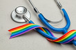 Stethoscope and LGBT rainbow ribbon pride symbol. Medical support after sex reassignment surgery. Grey background.