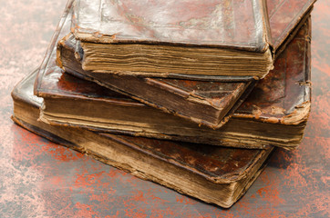 Poster - Stack of old and worn leather cover books with gold leaf embossing. Closeup