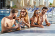 © Drobot Dean - Group of cheerful young friends sitting at the pool