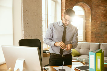 Management. A young businessman moving in the office, getting new work place. Young male office worker while managing after promotion. Looks happy. Business, lifestyle, new life concept. Unpacking.