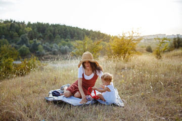 Wall Mural - Happy mother and daughter on the field at sunset.