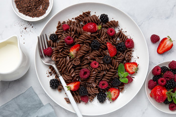 Sweet chocolate fusilli pasta with fresh berry on white plate