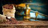Fototapeta  - Coffee beans in jute sacks with blurrred coffee machine view