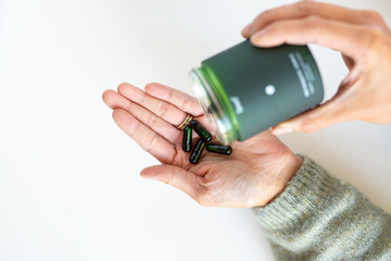 Vitamin Supplements in Green Jar Poured in Hand