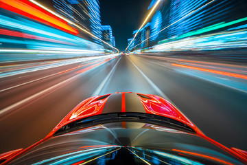 Wall Mural - View from roof of the red muscle car Car moving in a night city, Blured road with lights with car on high speed. Concept rapid rhythm of a modern city.