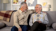 © motortion - Smiling senior men looking each other sitting home sofa friendship communication