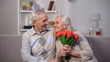 © motortion - Happy aged woman holding red tulips looking with love at senior husband, present