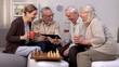 © motortion - Smiling pensioners watching online video tablet together, playing chess, hobby