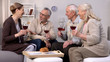 © motortion - Cheerful elderly friends with wine glasses talking relaxing home, leisure time
