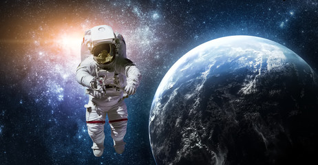 Wall Mural - astronaut in outer space near earth planet. galaxy on the horizon. abstract wallpaper. elements of t