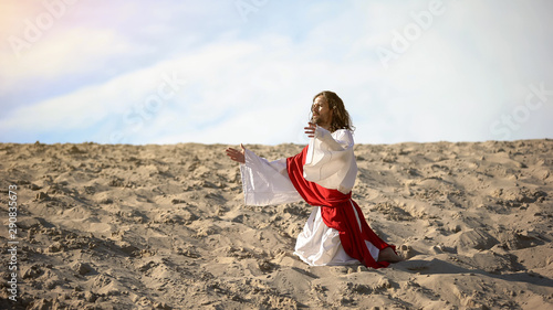Cuadros en Lienzo Male pilgrim in white robe kneeing in desert, asking help of Father God, faith