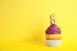Birthday cupcake with number five candle on yellow background, space for text