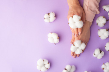 Wall Mural - well-groomed female hands with white delicate cotton flowers with space for design, on a purple background