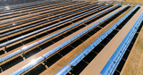 Fototapeta Miasto - Solar panels in a solar farm in Spain. There is the reflection of the sun in the the panels which produce renewable energy, solar energy - close-up with a drone - environment and renewable energy conc