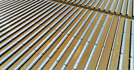 Solar panels in a solar farm in Spain. There is the reflection of the sun in the the panels which produce renewable energy, solar energy - aerial view with a drone - environment and renewable energy c