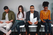 © StratfordProductions - Worried and stressed man holding his resume sitting with other candidates waiting for the job interview in office - diverse young group of candidates waiting for a job interview