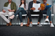 © StratfordProductions - Diverse candidates sitting in queue with their cv at office expecting their turn for interview - young and multiethnic group