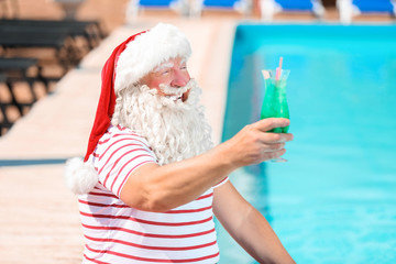 Wall Mural - Santa Claus with cocktail near swimming pool at resort