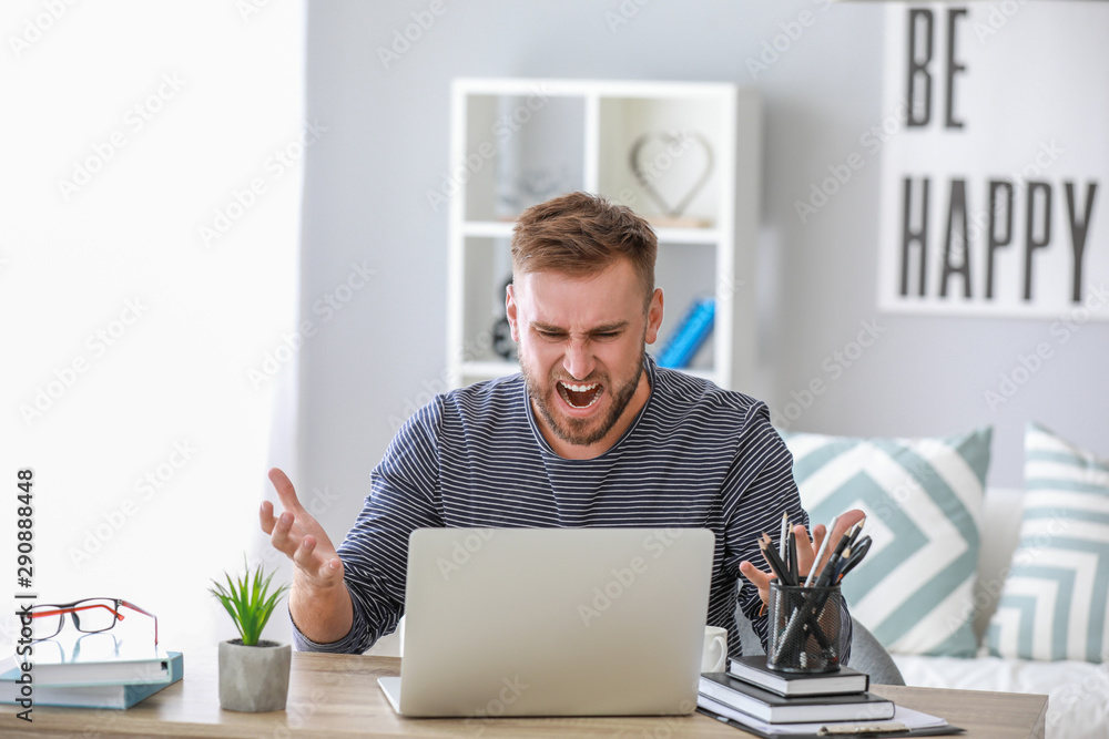Stressed young man at table in office