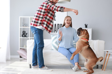 Sticker - Happy couple training cute dog at home