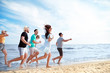 © Pixel-Shot - Happy friends running on sea beach at resort