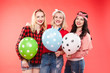 © Вячеслав Косько - Stock photo of three cheerful beautiful and stylish girls hugging and smiling at camera. They are holding colorful dotted air balloons. Isolate on red background.