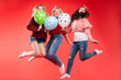 © Вячеслав Косько - Laughing woman friend having fun jumping and smiling with colorful air balloon isolated at red studio background. Happy female teenager celebrating enjoying party posing together full shot