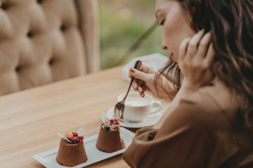 Crop photo of woman eating double tiramisu dessert decorated with fresh berries at cafe