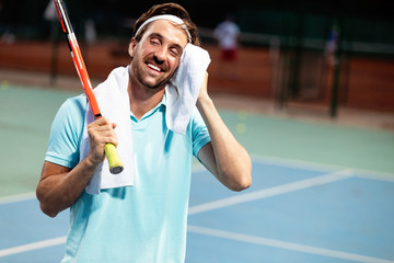 Tired tennis player man on tennis court with racket